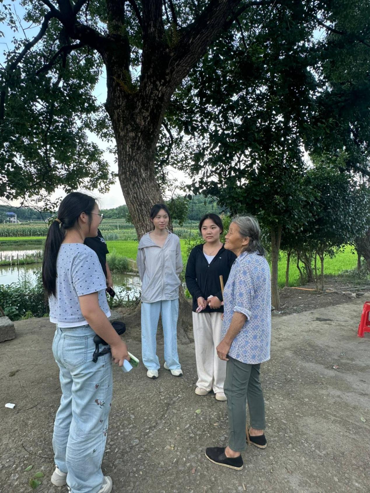 团队成员们在池塘边和老人进行防溺水知识的讲解