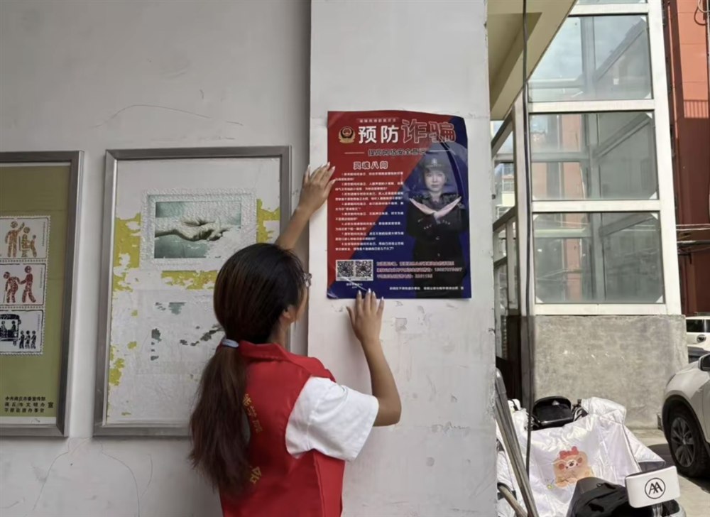 志愿者在社区张贴反诈宣传海报