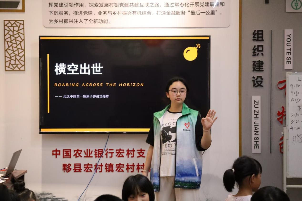 图为志愿者向孩子们讲解红色影片《横空出世》历史时代背景。