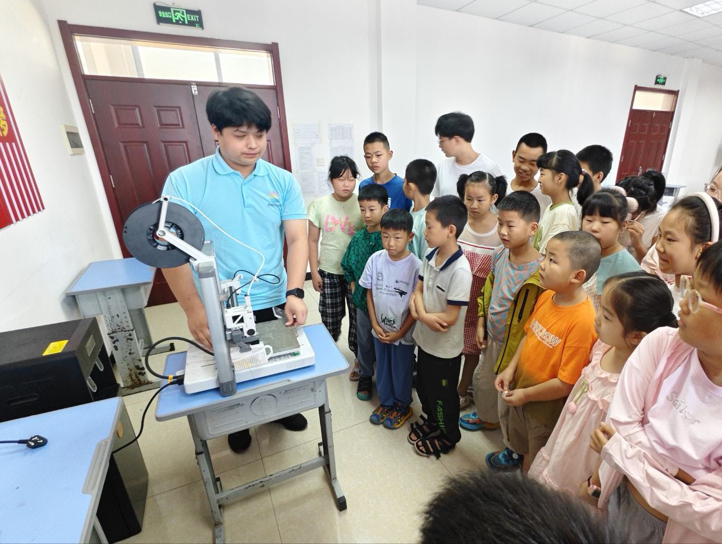 孩子们围聚在 3D 打印机周围,专注观看设备。志愿者结合实物开展现场教学,直观展示设备运作方式,激发乡村少年对工程、科创领域的好奇心与探索欲。