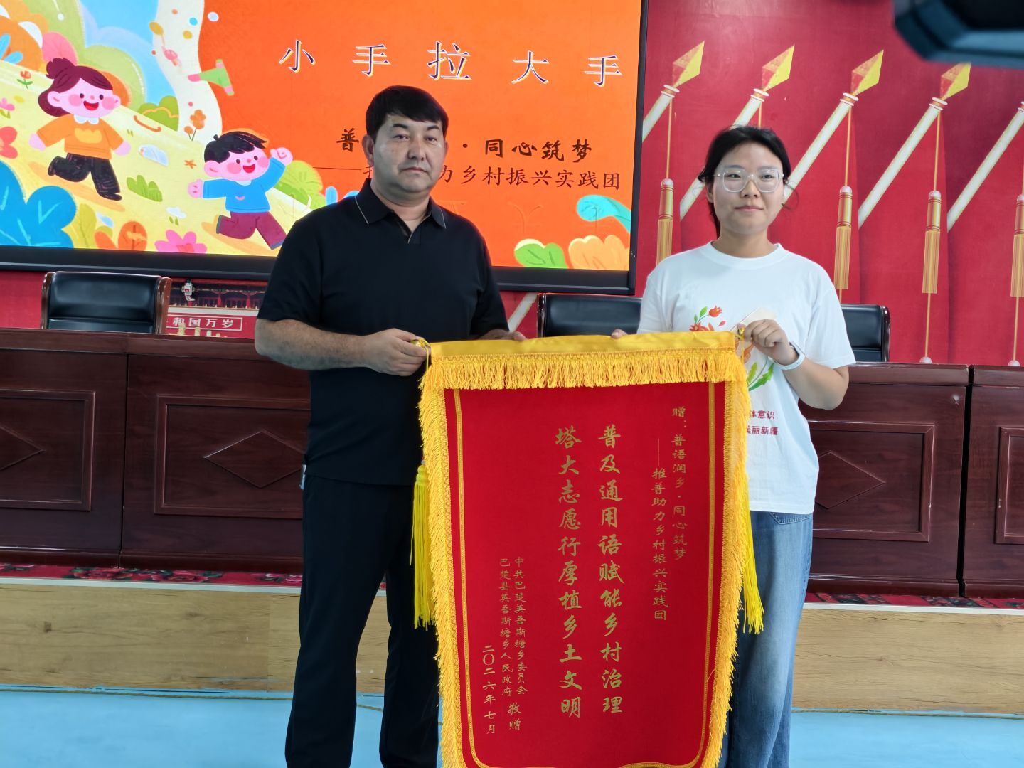 4. 配图4(授予锦旗) 巴楚县英吾斯塘乡乡长为塔里木大学推普实践团授予致谢锦旗
