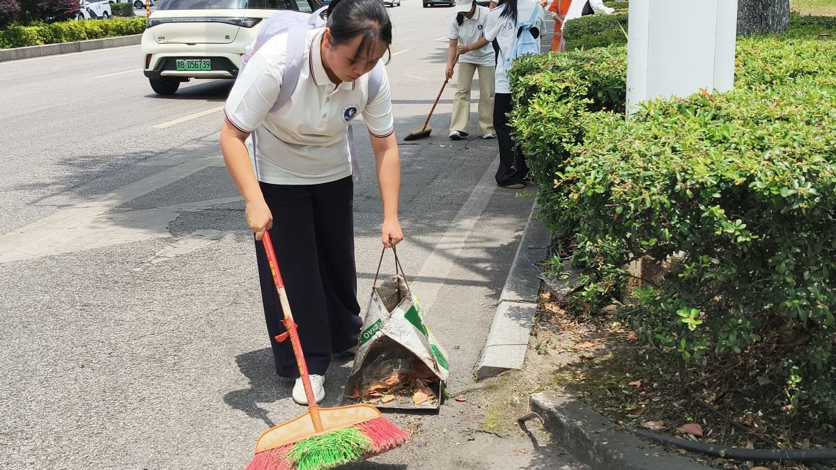 图为队员协助环卫工人清扫道路垃圾。吴延骄 供图