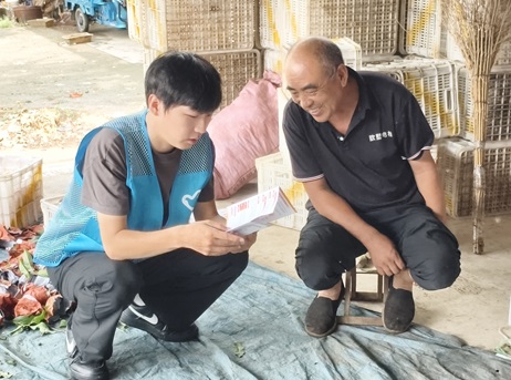 图 3:志愿者田间向农户发放资助政策明白纸