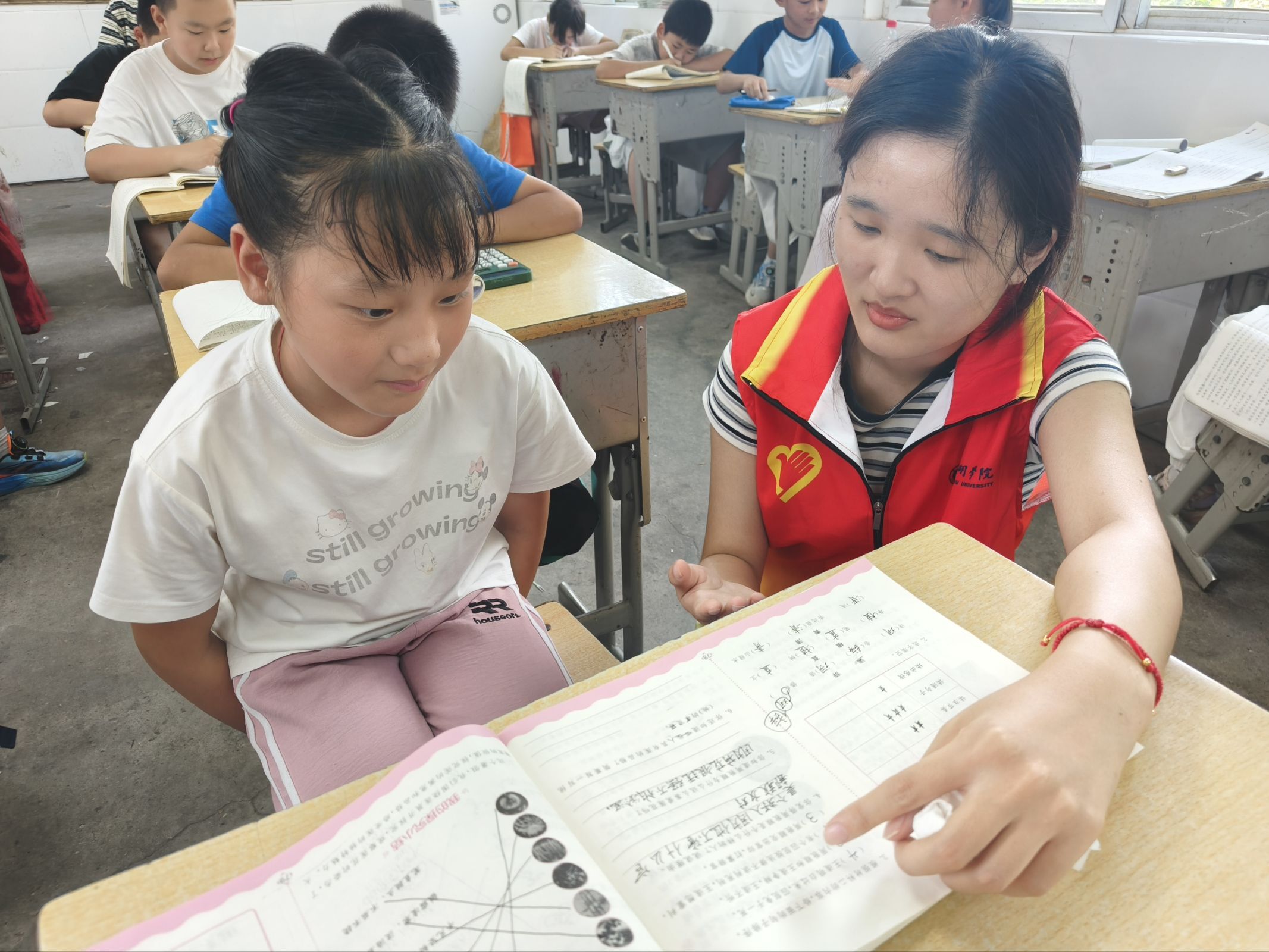 图 4 志愿者坐在孩子身边,逐题检查作业完成情况并指导订正。郭楠 供图